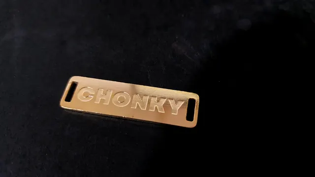 Polished brass slot label with raised lettering and strap slots